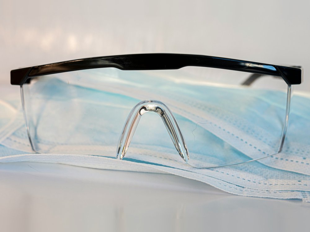 Schutzbrille auf einer OP-Maske, persönliche Schutzausrüstung